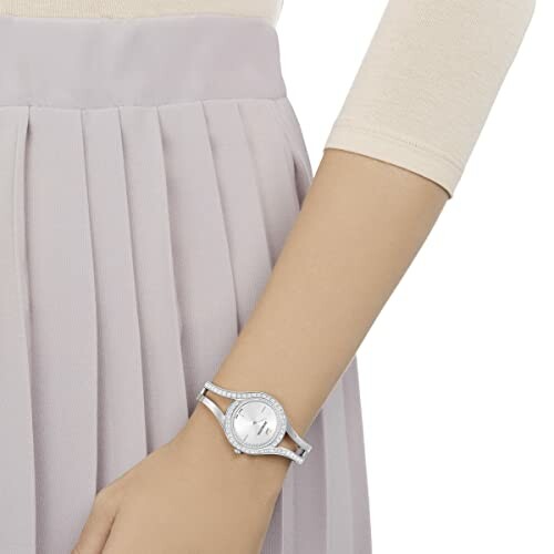 Woman wearing a silver watch with a pleated skirt.