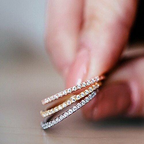Close-up of a hand holding three thin diamond rings.