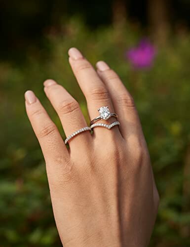 Hand wearing rings with diamond and nature background.