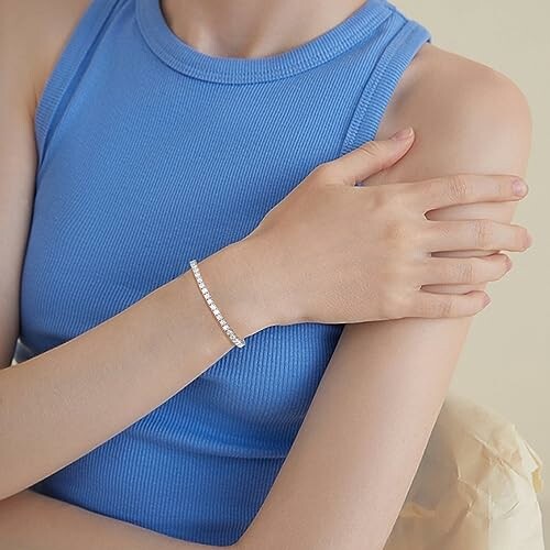 Woman in blue top wearing a bracelet on her wrist.