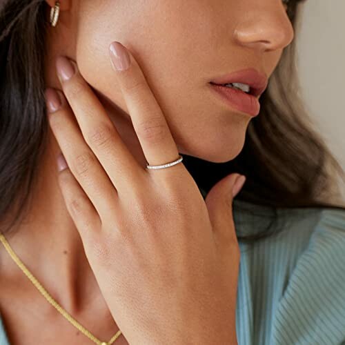 Woman touching face with hand wearing a simple ring.