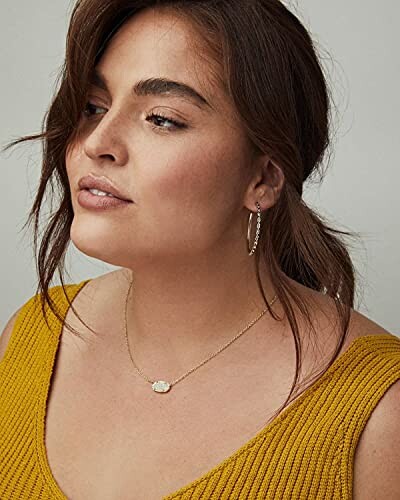 Woman wearing a yellow top, necklace, and hoop earrings.